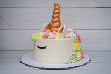 beautiful homemade cake in the shape of a unicorn on white wooden background
