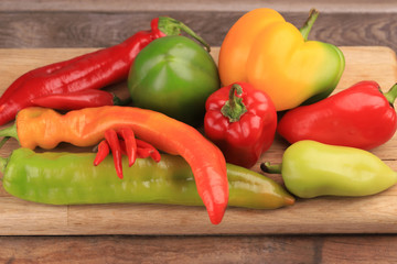 Various types of sweet and hot pepper on  a wooden background
