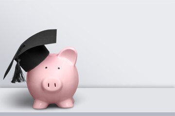 Piggy Bank with Black Graduation Hat on wooden background