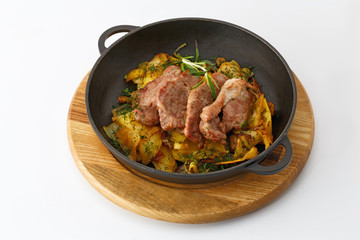 fried potatoes with meat in a cast iron pan on a wooden board isolated on white background