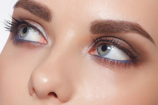 Close-up of female eyes with trendy evening make-up, thick even eyebrows and long rustnitsami. Gray-blue eyes, lenses, eyesight, cosmetology, make-up
