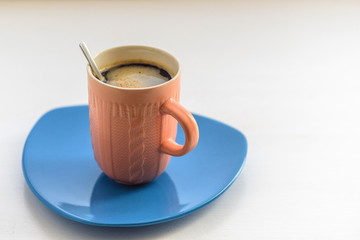 A cup of coffee on a blue plate.