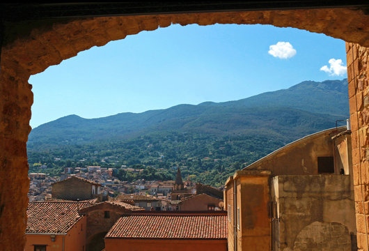 view through a door arch to an italian town and mountains