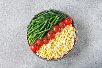 Vegan bowl with bulgur, green beans and cherry tomatoes. Healthy food with vegetables and bulgur. Superfoods Dietary nutrition.
