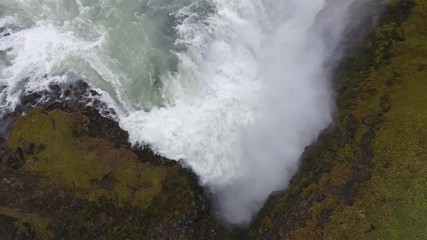 Aerial drone shot flying Gulfoss waterfall in Iceland. Cloudy day; low altitude flight, vertical view to horizon. - Powered by Adobe