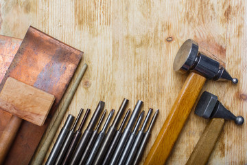 Copper embossing tools set on vintage wooden background. Metal embossing tools. Hammered steel...