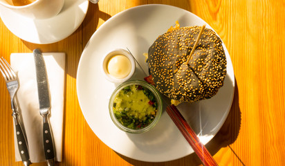 Black burger with egg, sauce and vegetable salad