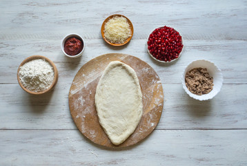 Preparation of traditional Arabic pizza manaqish with meat and pomegranate.
