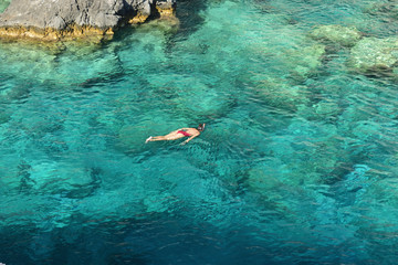 Young woman snorkeling in the turquoise waters at Plakaki Cape, Zakynthos Island, Greece