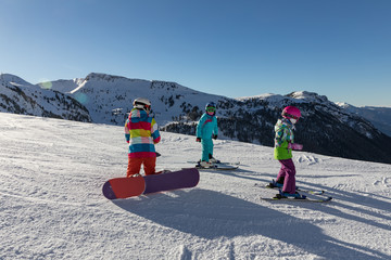 Cute children in colorful overalls on the ski slope. Small skiers and snowbords on the Dolomites...