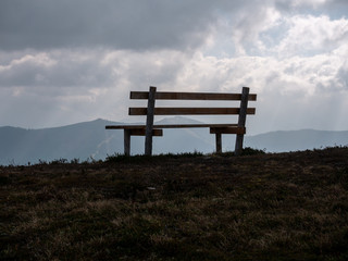 Image with focus of bench with mountains in the background