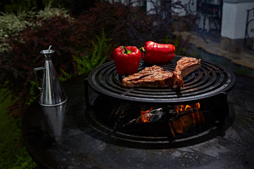 Tomahawk rib beef steak and T-bone on hot black grill.