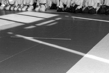 People in kimono sitting on tatami on martial arts weapon training seminar. Black and white