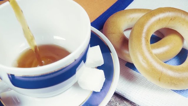Slow motion pour tea into a beautiful blue white Cup with a saucer near the bagel Baranka