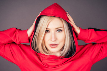 portrait of a beautiful blonde woman perfect skin and makeup put on hood hoodie sweatshirt red...