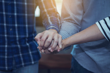 three person join hand and pray together in office