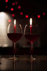 Romantic dinner: two glasses of wine and candels are in the dark with new year lights at the background