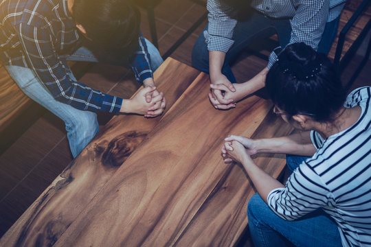 Christian people prays together around wooden table. prayer meeting small group concept.