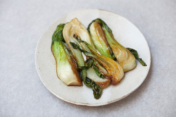 Close-up image of pan fried bok choy on a white background in soft focus