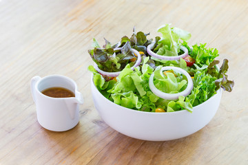 Mixed salad with source in white bowl.