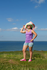 A young woman stands on a mountain and admires the nature.