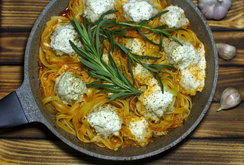 spaghetti nests with chicken meatballs and sour cream sauce on dark table