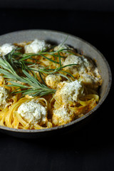spaghetti nests with chicken meatballs and sour cream sauce on dark table