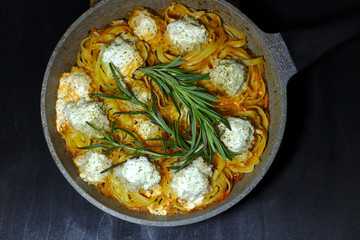 spaghetti nests with chicken meatballs and sour cream sauce on dark table