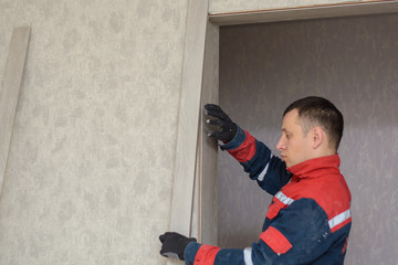 Male carpenter at interior wood installation and working with level measuring tape
