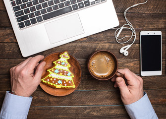 Man working on Christmas time. Christmas workspace with laptop, phone, coffee mag, Christmas tree...