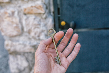 Old vintage brass door Key in mans hand