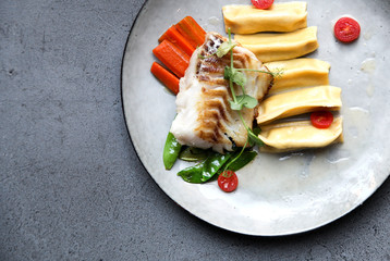Fillet of cod with dumplings, carrots, green sweet pea and tomatoes