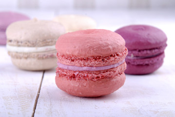 Composition of multicolored macaroon on a white wooden background.