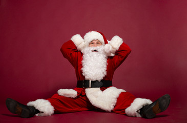 Shocked Santa Clause sitting on red background, Christmas and New year concept