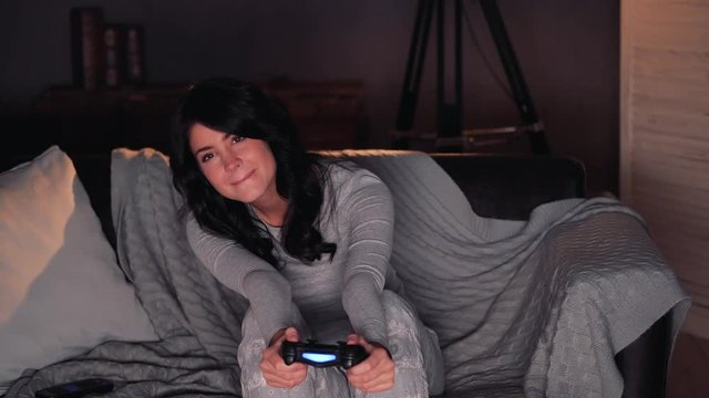woman playing videogame on console and wins. Sitting on sofa at home
