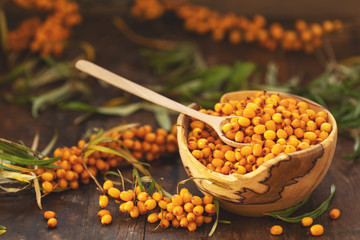 Natural, organic sea buckthorn berry in bowl on dark wooden background