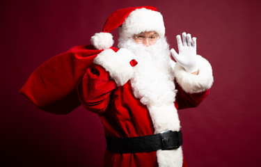 Portrait of grandfather in Santa Clause costume with gift sack on back posing on red background, Christmas and New year concept