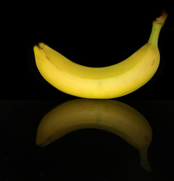 a yellow banana isolated on black background with mirror reflection