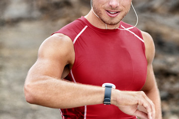 Smartwatch man athlete runner checking his wearable device tech smart watch during outdoor training...