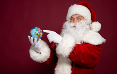 Santa Clause with earth globe on hand on red background, Christmas and New year concept