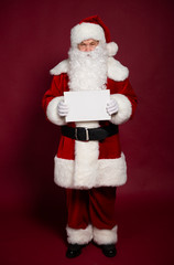 Happy grandfather Santa Clause showing white blank poster or board on red background, Christmas and New year concept