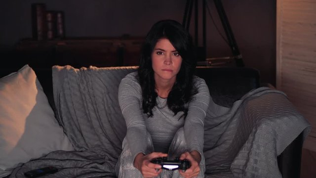 woman playing videogame on console and Loose. Sitting on sofa at home