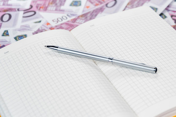 Diary with a pen on the money