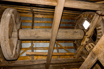 Fototapeta na wymiar Interior and mechanism of an old wooden mill of the 18th century. Wooden gears and main shaft grinding grain genuine obsolete technologies of the past. Natural light. Ukraine, Odessa