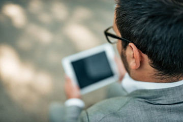 Close-up image of a businessman using digital tablet outdoors. High angle view.