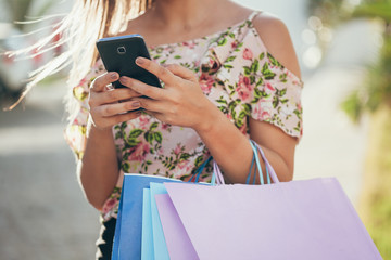 Shopper woman hand shopping with a smart phone and carrying bags