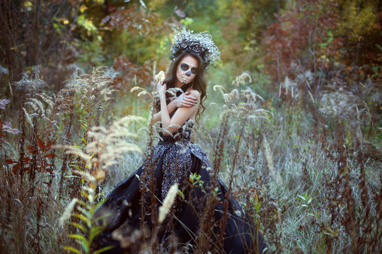Portrait of a young woman with make-up for Halloween in a fairy forest.