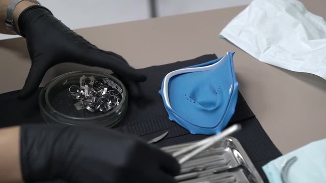 Tools for installing the cofferdam (rubberdam and clamp) lying on the table a black background in clinic
