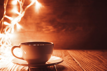 Obraz premium a Cup of coffee on a wooden background in the background garland