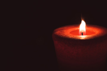 lonely flame burning red candle in the dark
